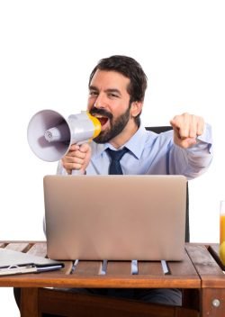 Businessman in his office shouting by megaphone