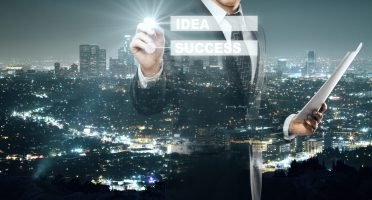 Businessman with document in hand drawing digital business scheme on illuminated night city background. Idea concept. Double exposure